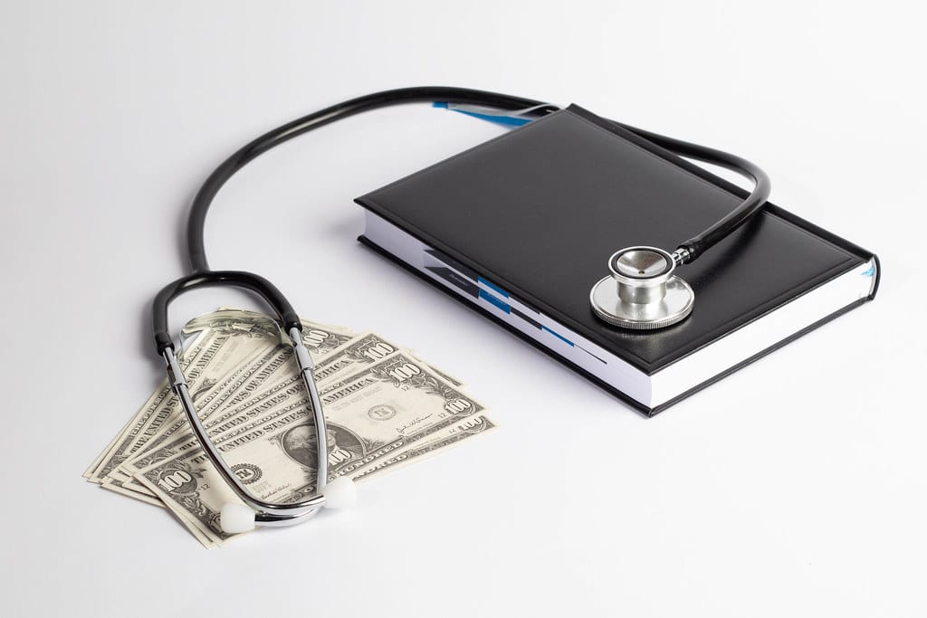 Image of stethoscope laid over scheduling book and money